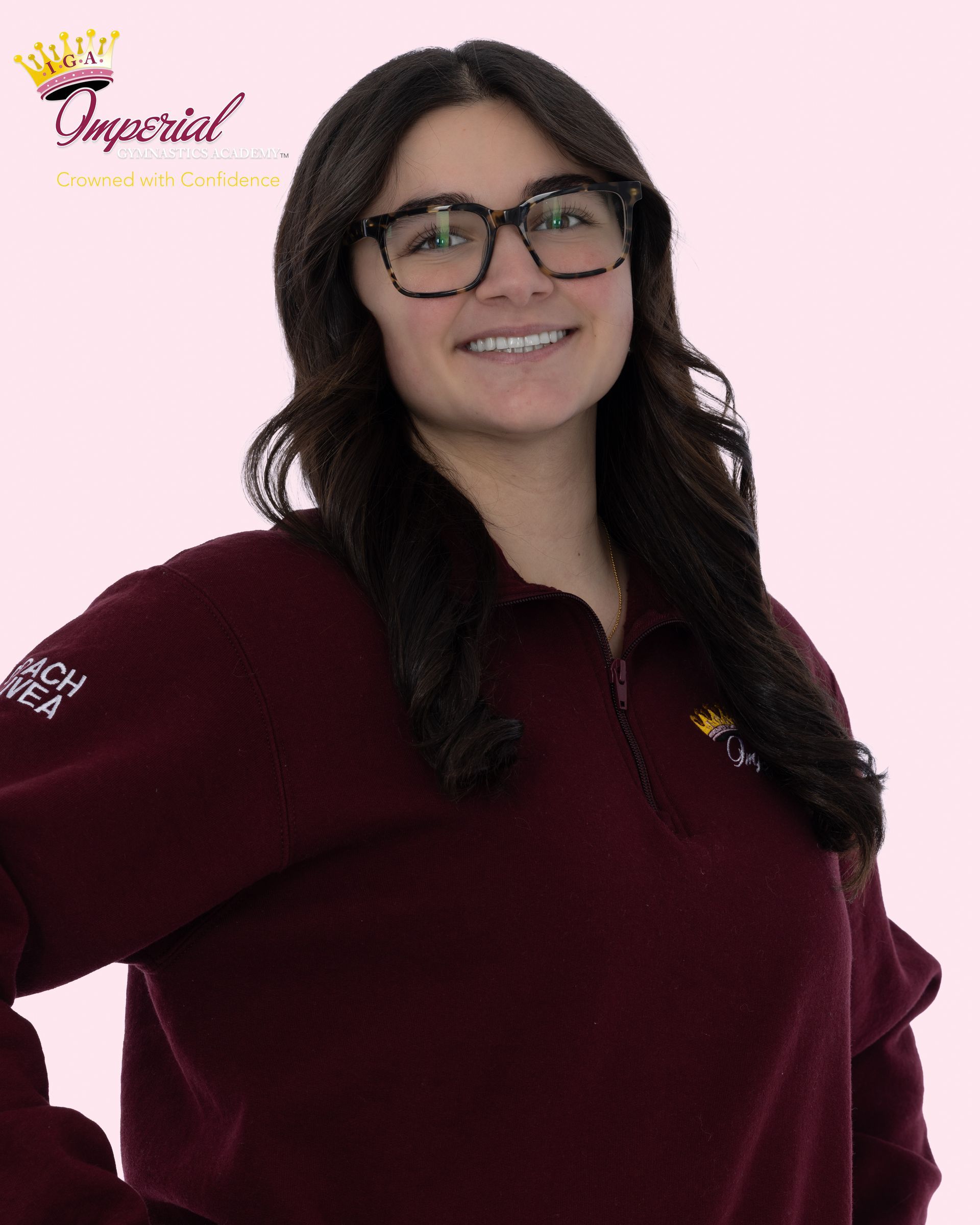 Woman with glasses and pink shirt, arms crossed, smiling.