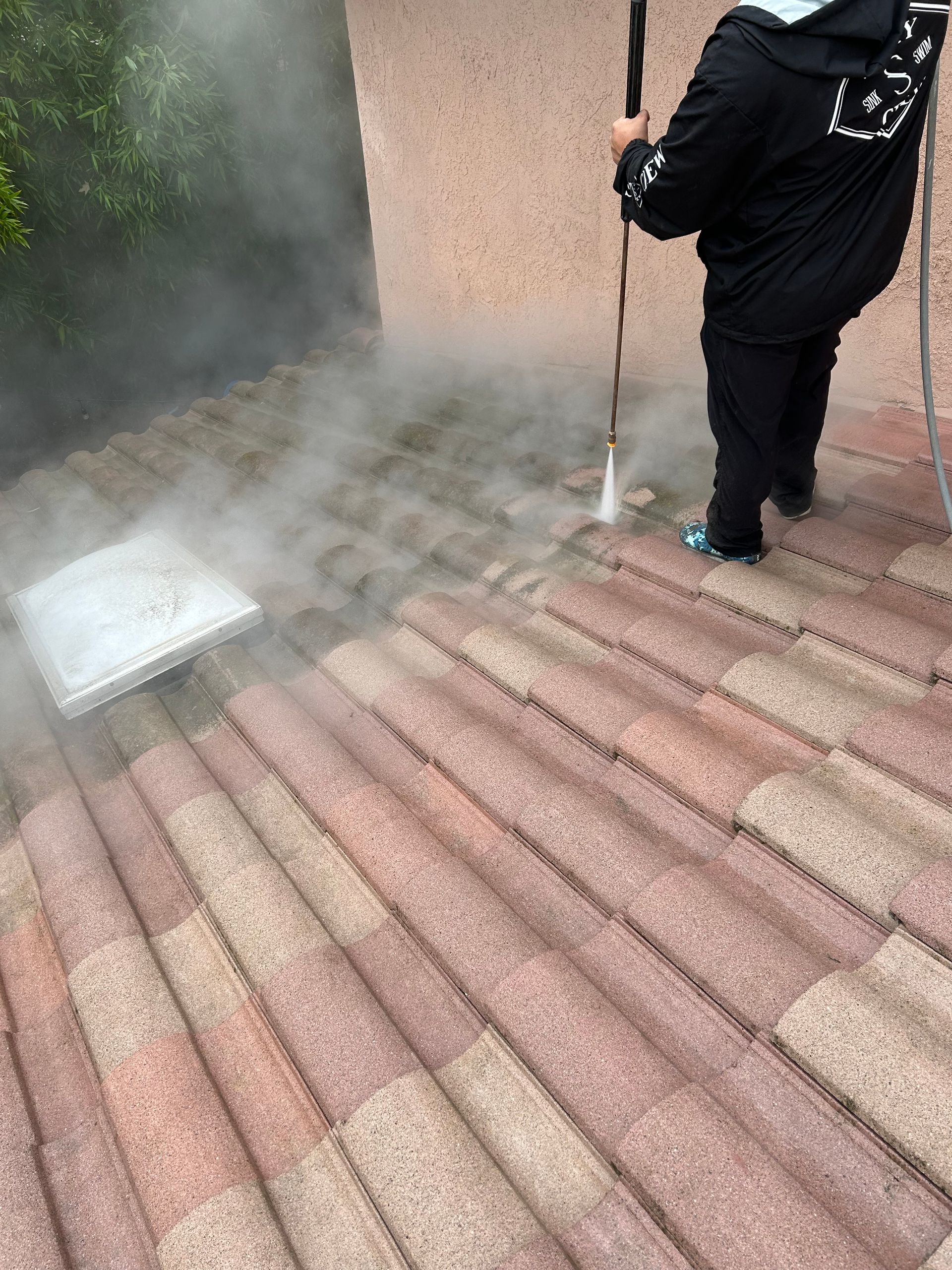 A person is cleaning a brick patio with a high pressure washer.