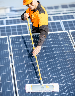 A man is cleaning solar panels with a mop