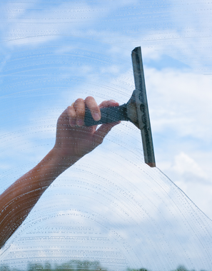 A person is cleaning a window with a squeegee.