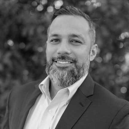 Nova Point Digital Project Manager Felix Nieves in a white shirt and tie is sitting in a car.