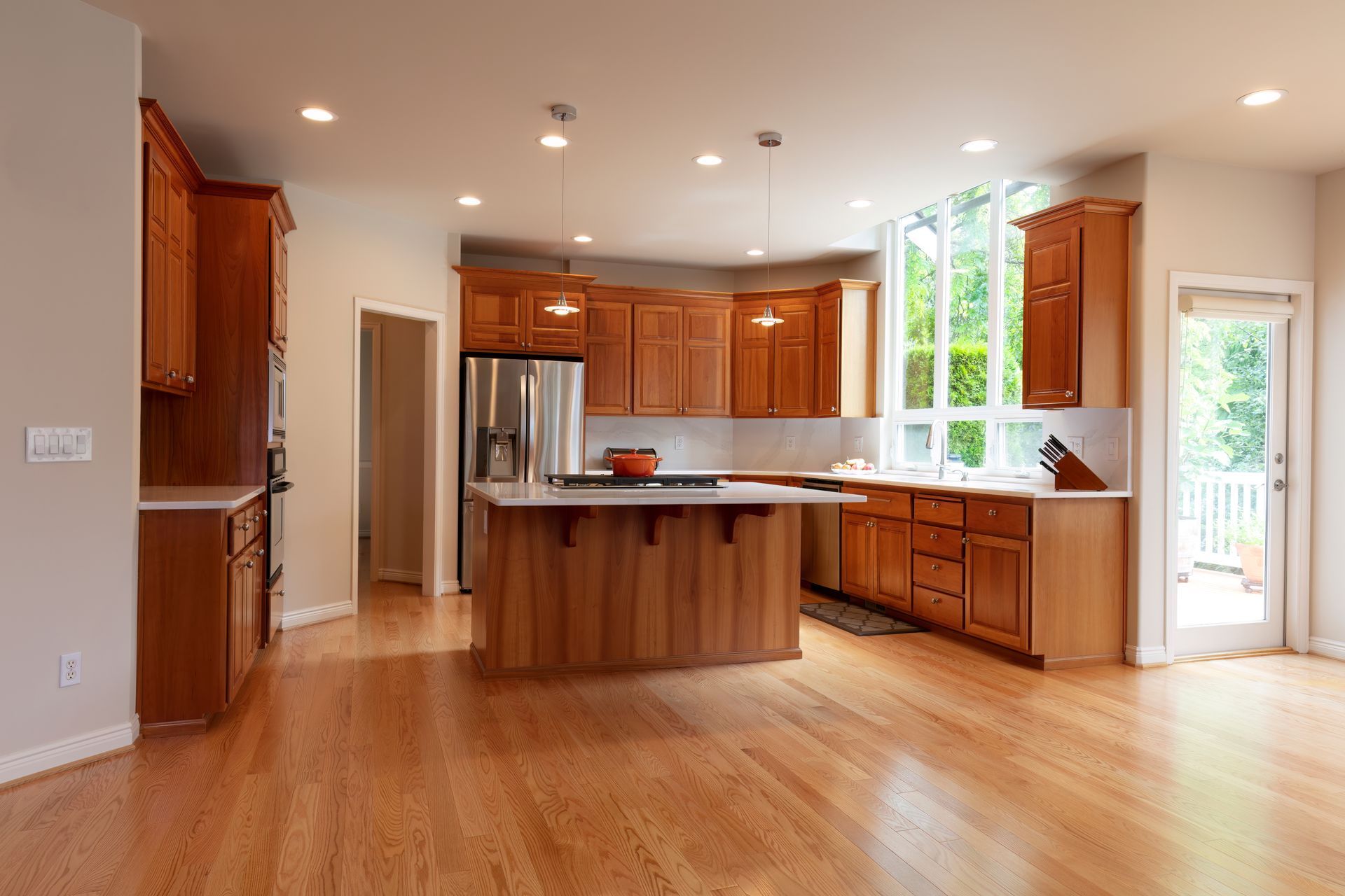 An empty kitchen with wooden cabinets and hardwood floors.