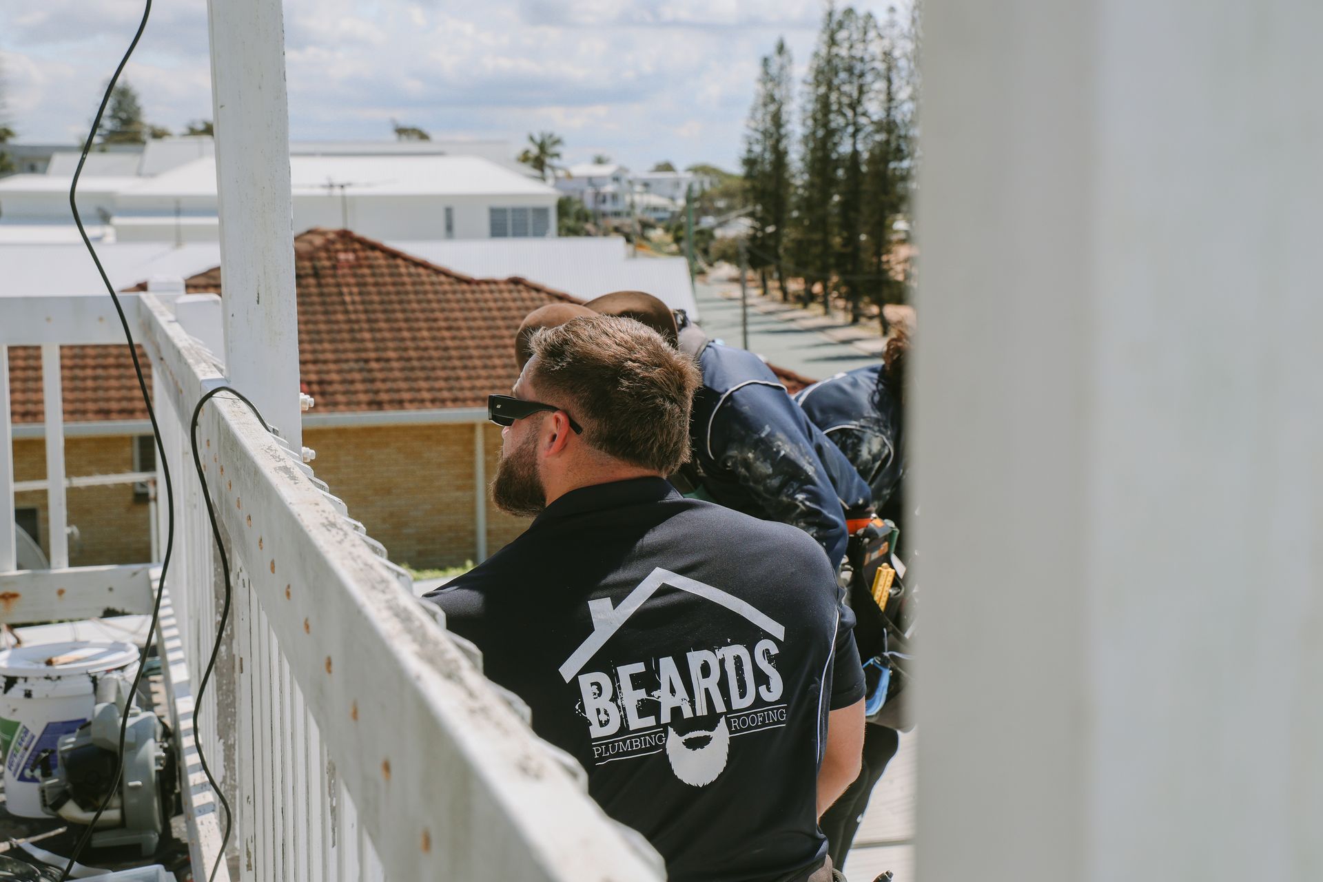 A Man Wearing a Black Shirt is Standing on a Balcony — Beards Roofing and Plumbing in Clontarf, QLD