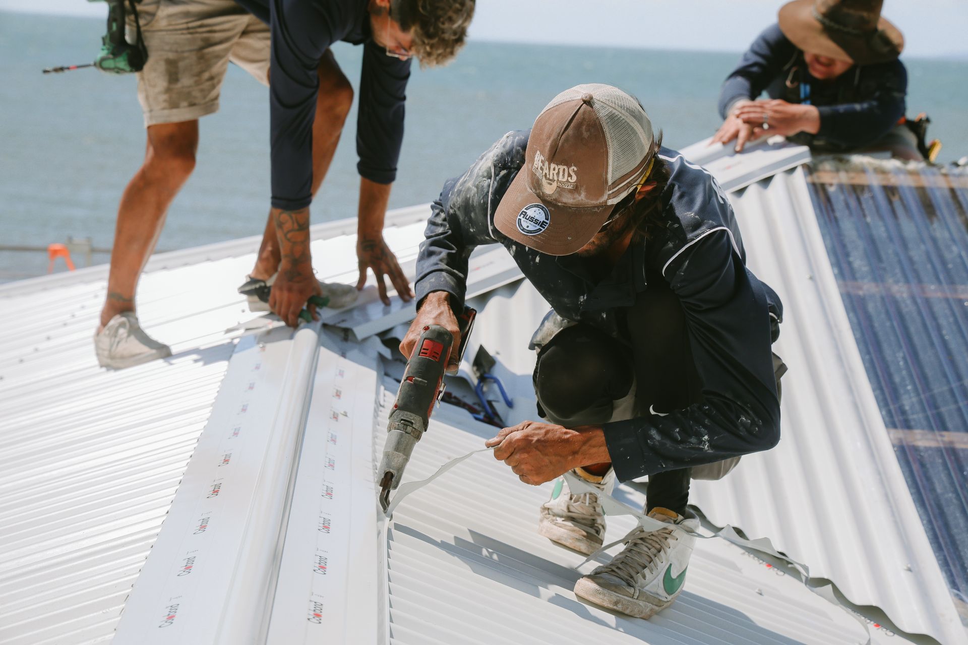 A Group of People Are Working on the Roof of a Building — Beards Roofing and Plumbing in Bribie Island, QLD