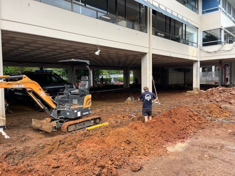 A Man is Digging in the Dirt in Front of a Building — Beards Roofing and Plumbing in Bribie Island, QLD