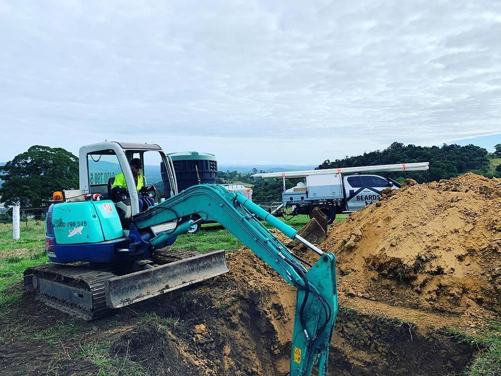 A Small Excavator is Digging a Hole in the Ground — Beards Roofing and Plumbing in Morayfield, QLD