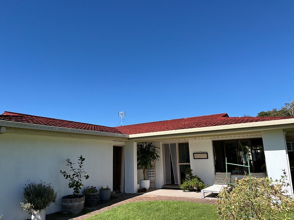 A White House With a Red Roof and a Blue Sky in the Background — Beards Roofing and Plumbing in Redcliffe, QLD