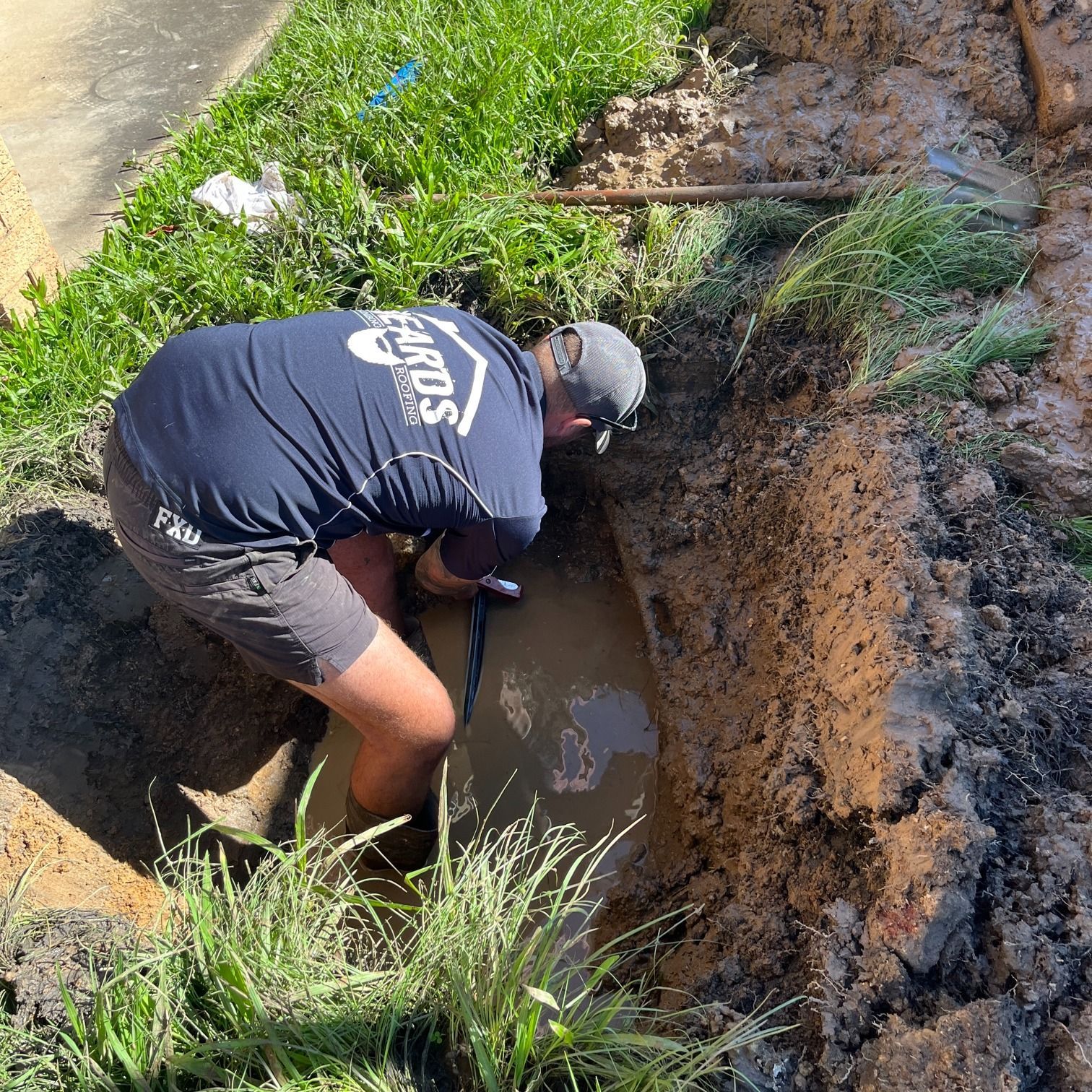 Man in a Blue Shirt is Digging in the Dirt — Beards Roofing and Plumbing in Clontarf, QLD