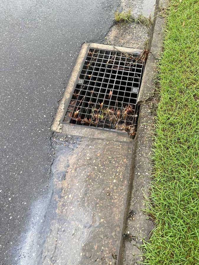 A Drain on the Side of a Road Next to a Grassy Area — Beards Roofing and Plumbing in Kallangur, QLD