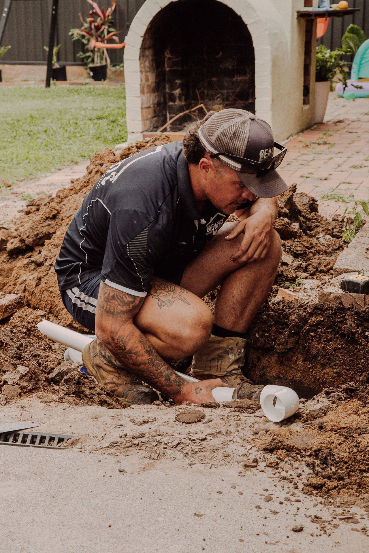 Man is Kneeling in the Dirt Working on a Pipe — Beards Roofing and Plumbing in Clontarf, QLD