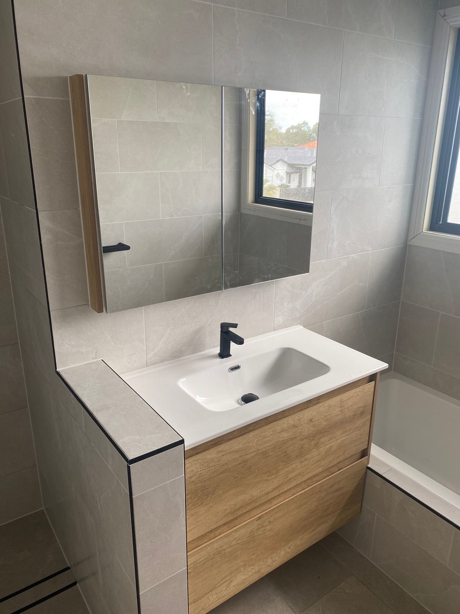 Bathroom With a Sink, Mirror and Bathtub — Beards Roofing and Plumbing in Clontarf, QLD