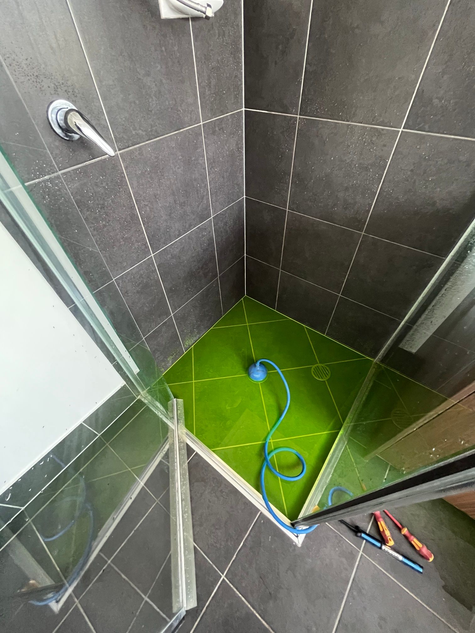 Shower Stall With a Green Tile Floor and a Hose in It — Beards Roofing and Plumbing in Clontarf, QLD