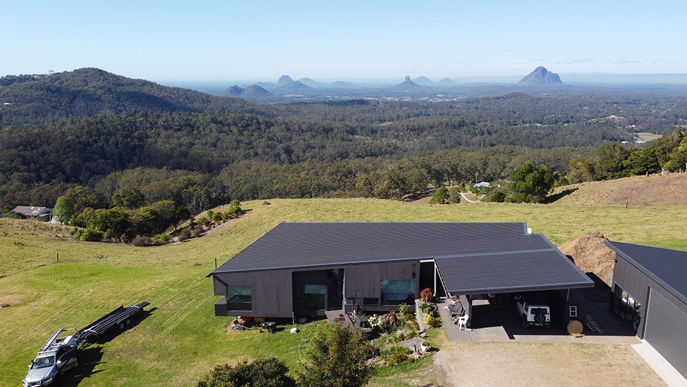 An Aerial View of a House on Top of a Hill With Mountains in the Background — Beards Roofing and Plumbing in Morayfield, QLD
