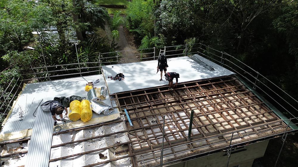 A Group of People Are Working on the Roof of a Building — Beards Roofing and Plumbing in Clontarf, QLD