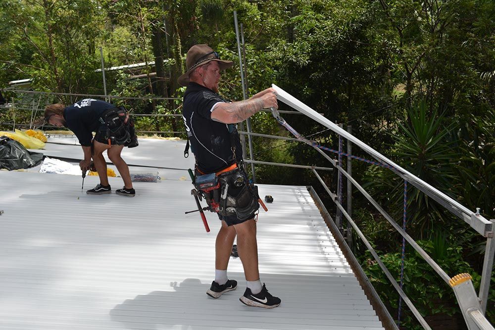 A Man is Standing on a Bridge Holding a Railing — Beards Roofing and Plumbing in Clontarf, QLD