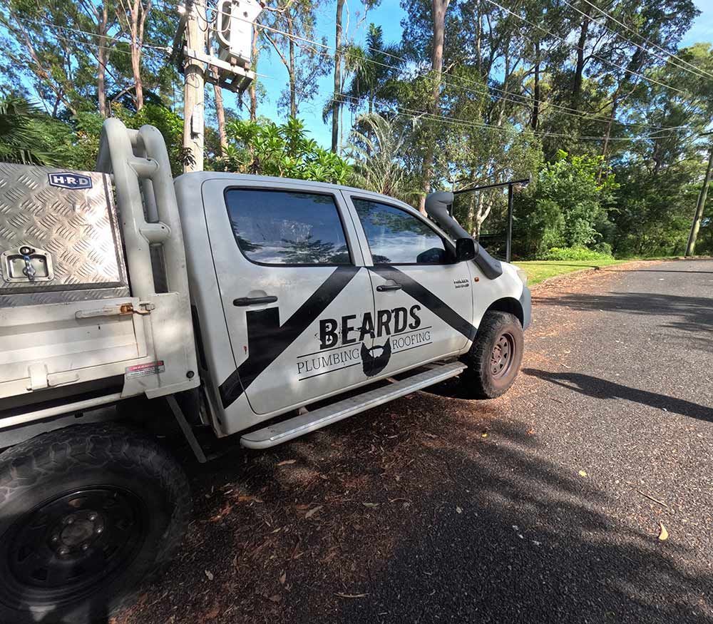 A White Truck With the Word Beards is Parked on the Side of the Road — Beards Roofing and Plumbing in Clontarf, QLD