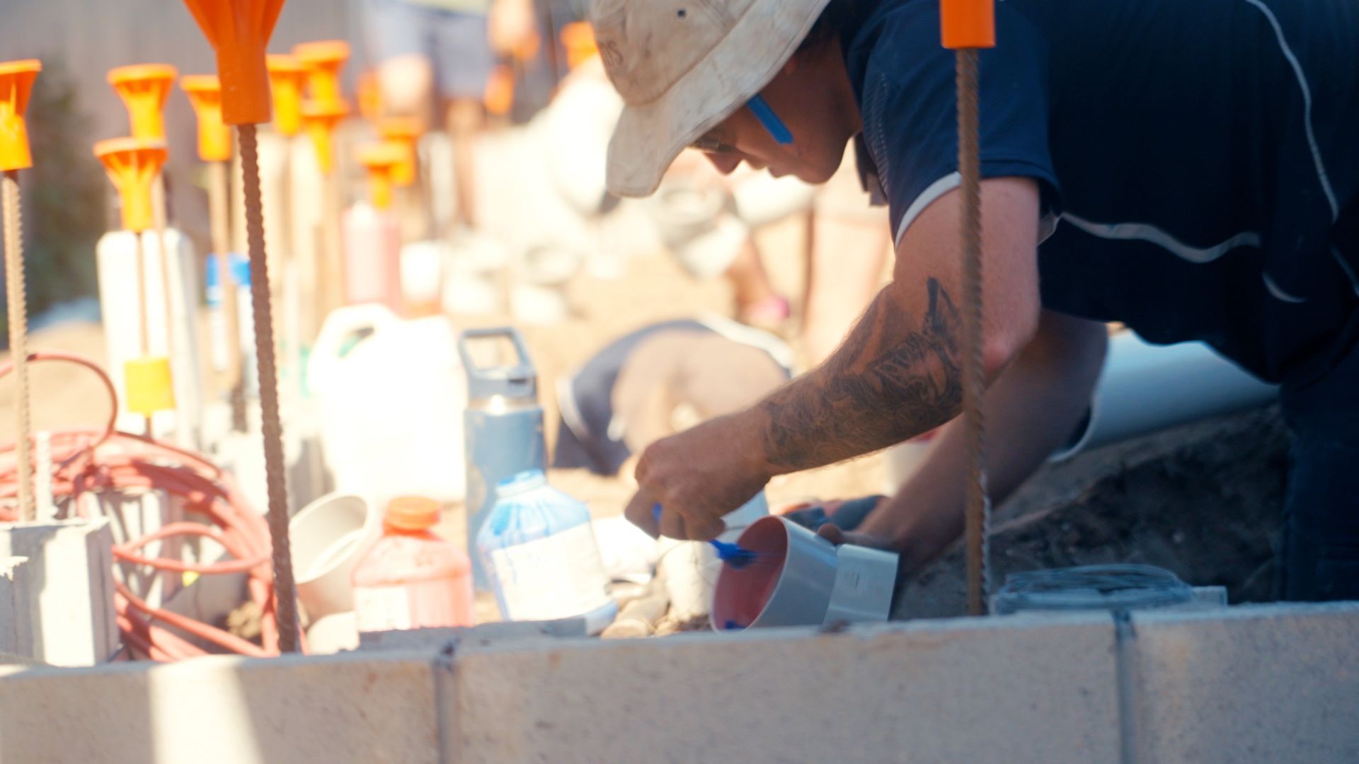 A Man is Bent Over Doing A Plumbing Job — Beards Roofing and Plumbing in Morayfield, QLD