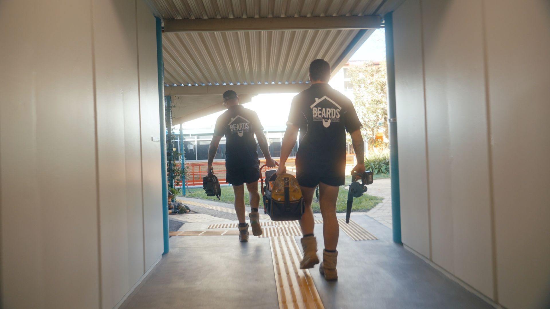Two Plumbers Carrying Work Tools — Beards Roofing and Plumbing in Burpengary, QLD
