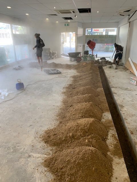 A Man is Standing in a Room With a Lot of Dirt on the Floor — Beards Roofing and Plumbing in Caboolture, QLD