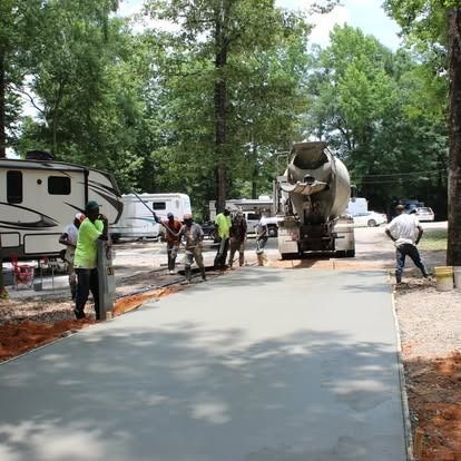 A group of people are working on a concrete driveway.