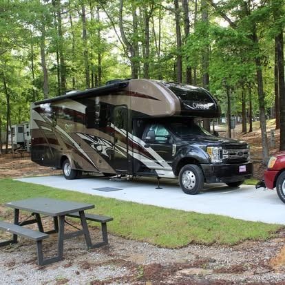 A rv is parked in a parking lot next to a picnic table