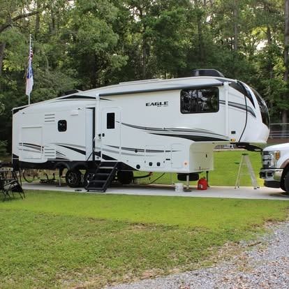 A white eagle trailer is parked in a grassy area