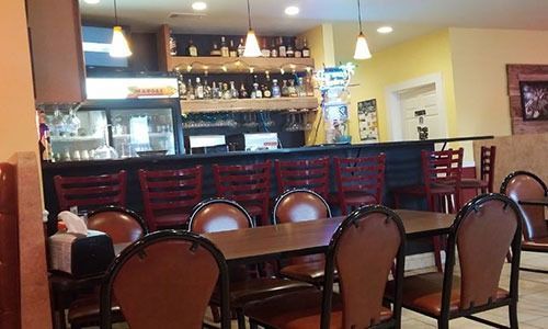 A restaurant with tables and chairs and a bar.