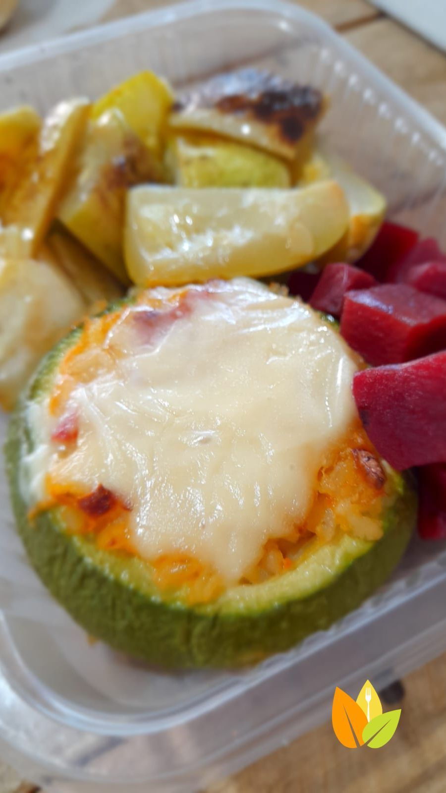 Calabacines rellenos de queso fundido, verduras asadas y remolacha encurtida en un recipiente de plástico.