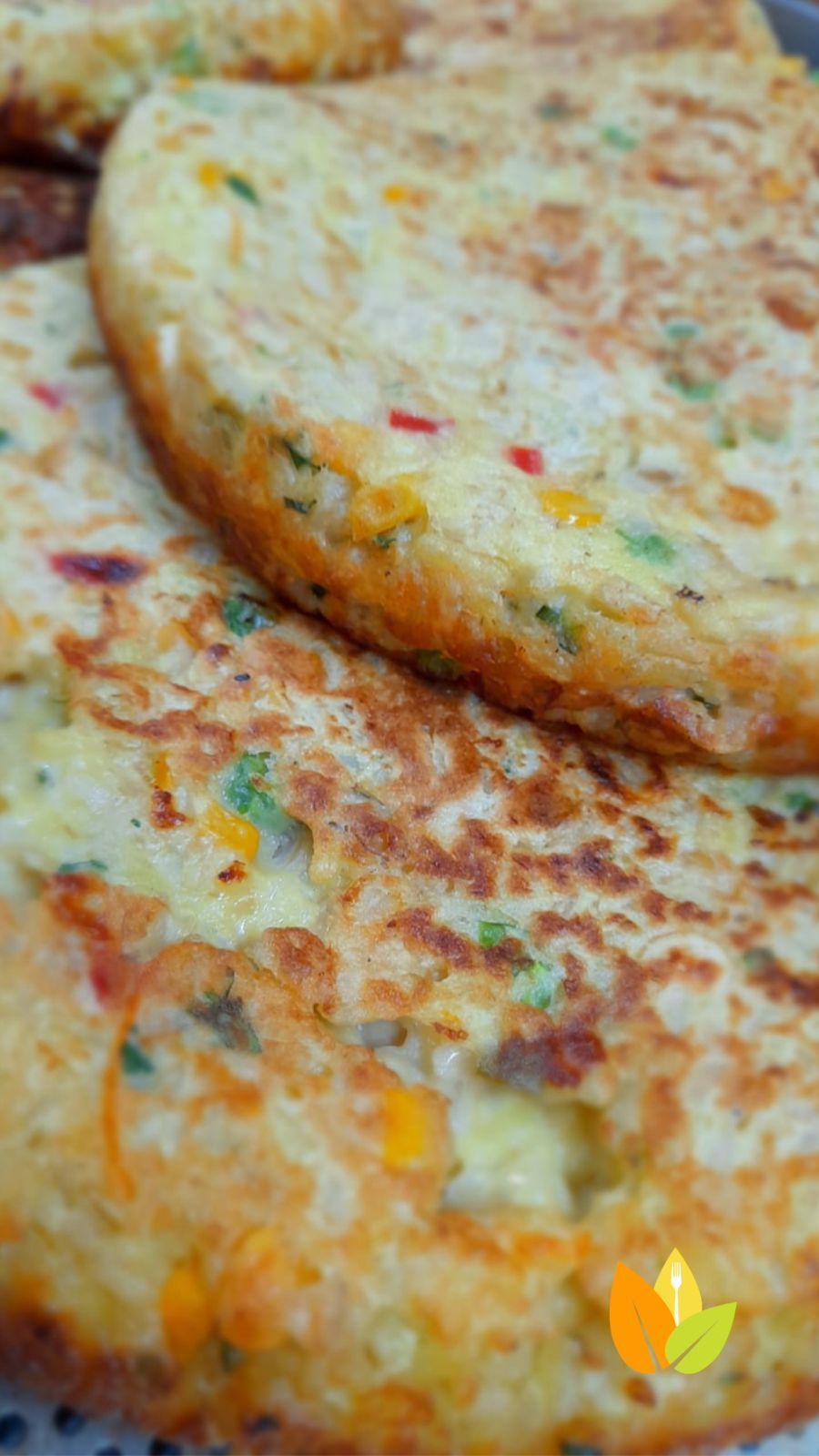 Primer plano de buñuelos de verduras dorados, donde se aprecian trozos visibles de verduras coloridas.