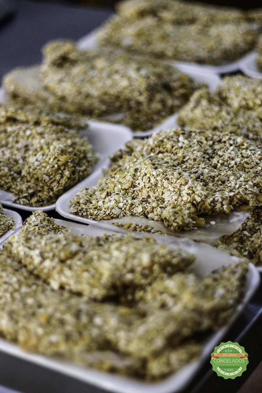 Porciones de comida empanizada en bandejas blancas, listas para cocinar.