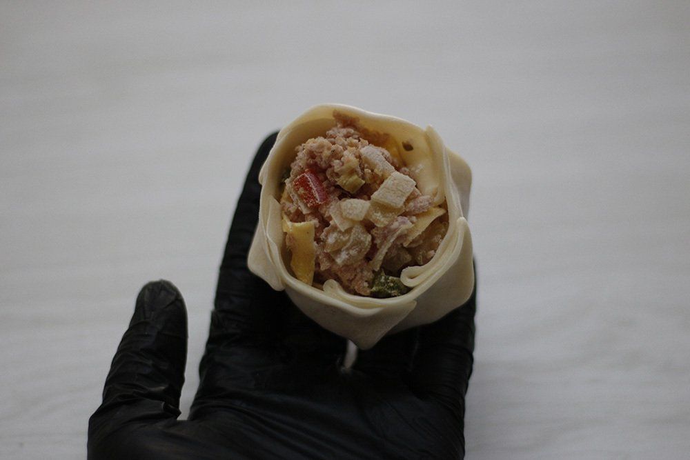 Mano sosteniendo un wrap relleno y doblado con los ingredientes visibles.