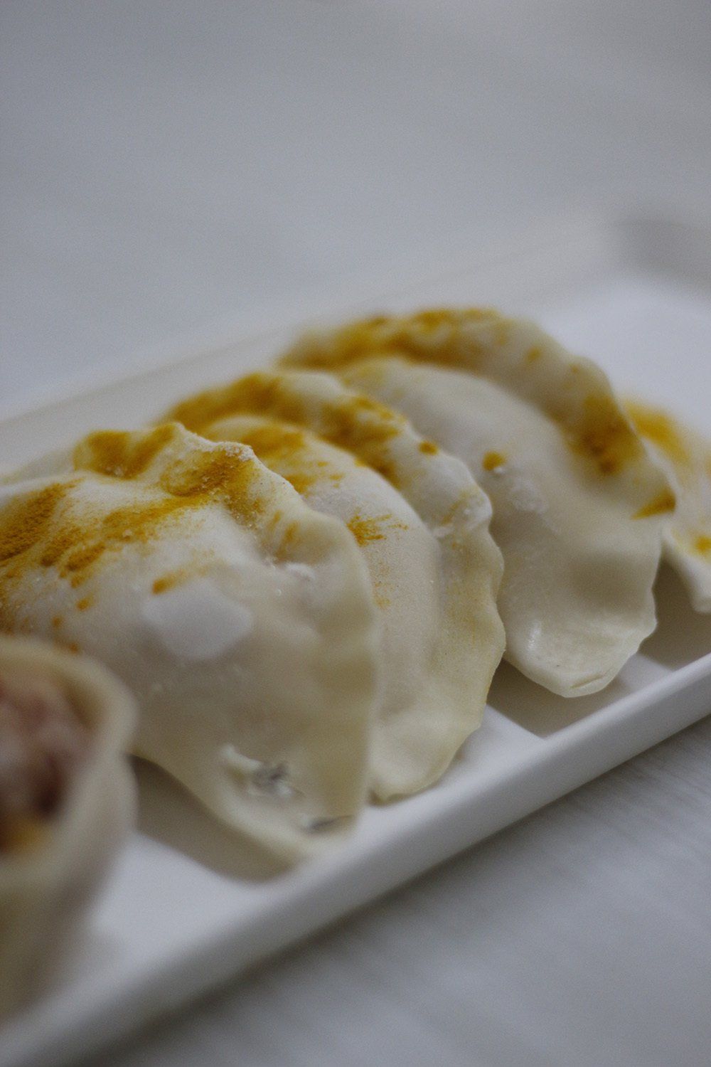 Empanadillas en un plato blanco, espolvoreadas con condimento amarillo.