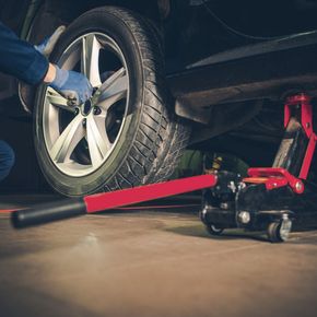 A person is changing a tire on a car with a jack.