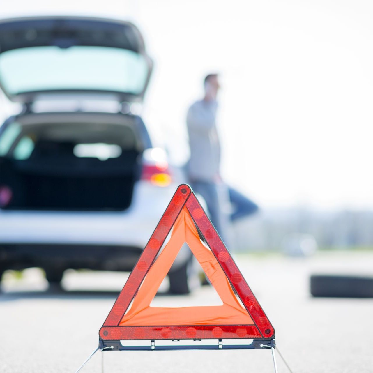 A warning triangle in front of a car with the trunk open