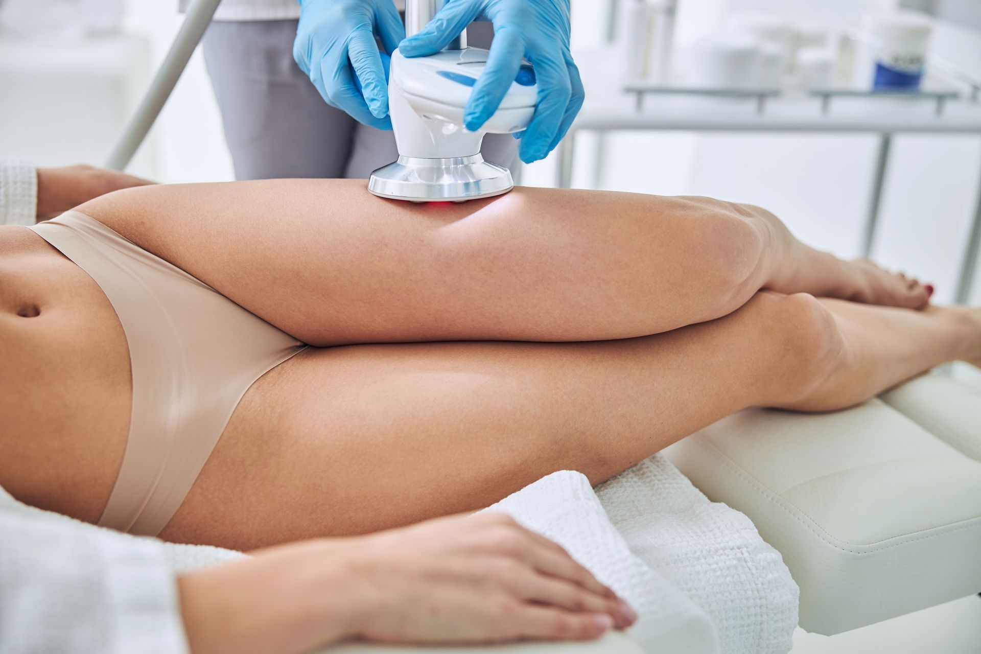 A woman is getting a cavitation treatment on her legs.