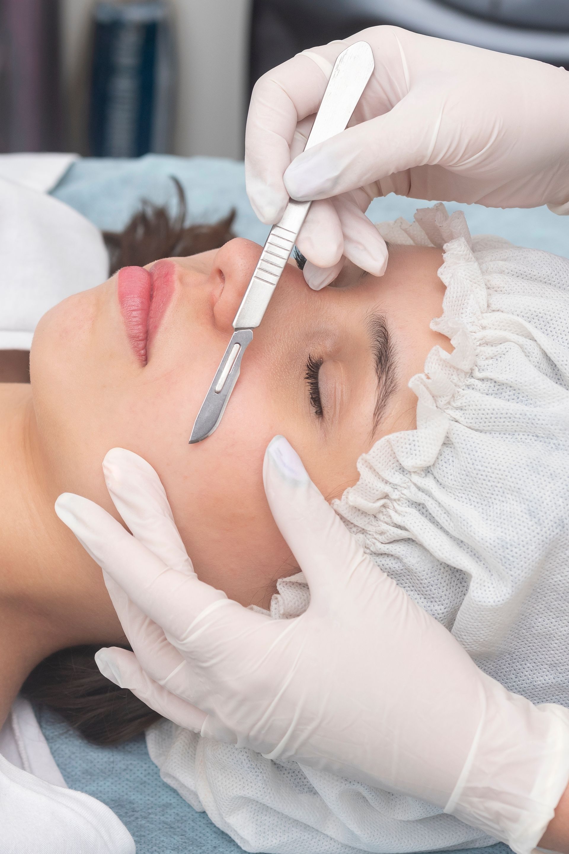 A woman is getting a facial treatment with a scalpel.