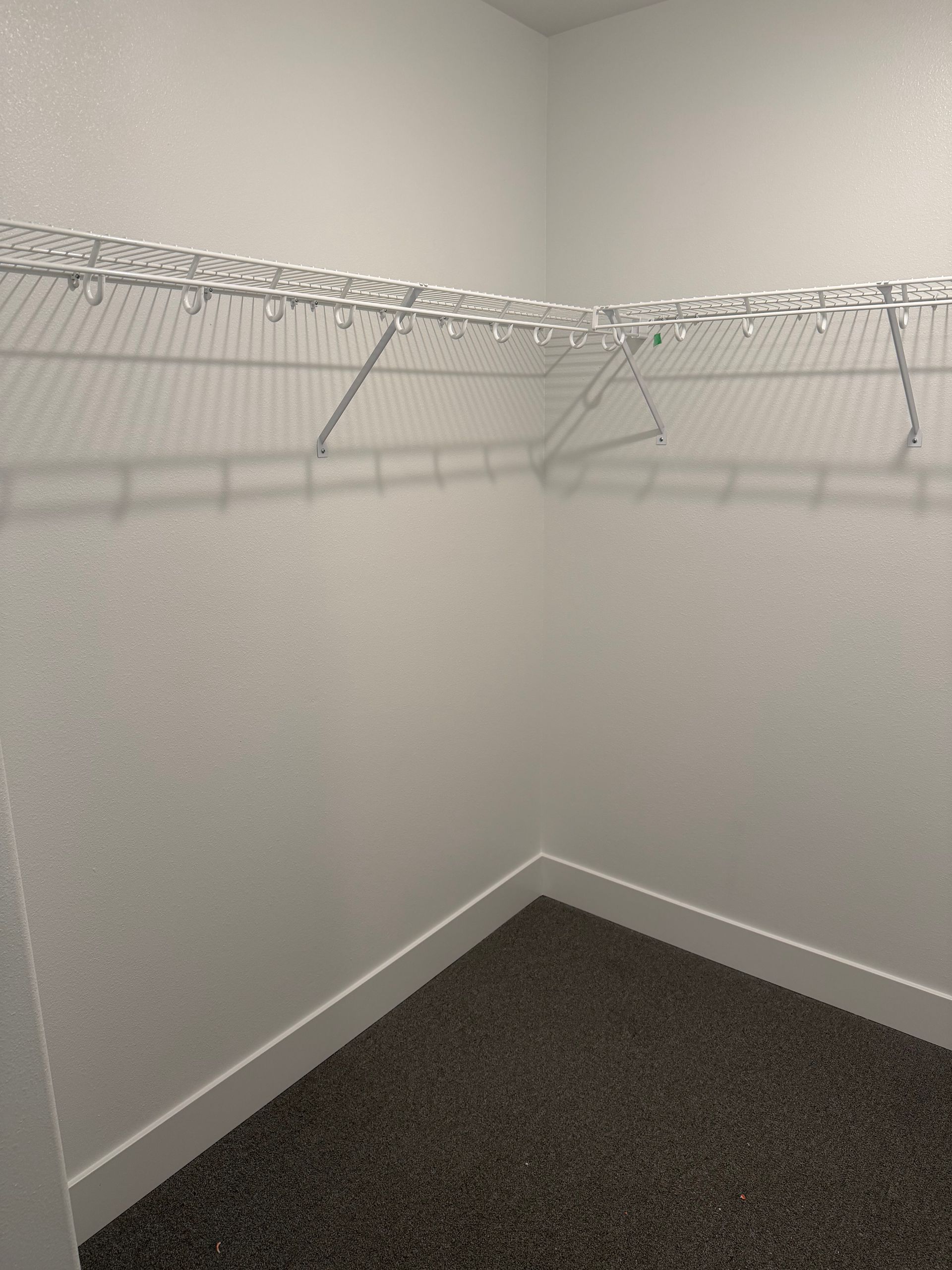Empty white closet with wire shelving and gray carpet.