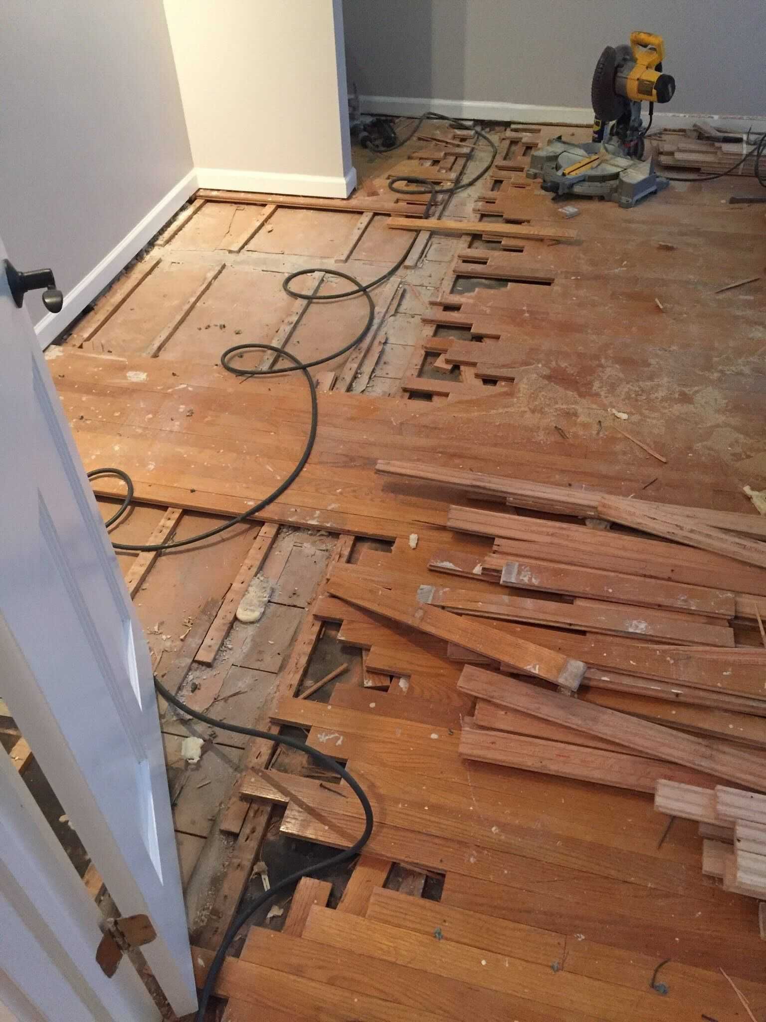 A room with a lot of wood on the floor and a saw.