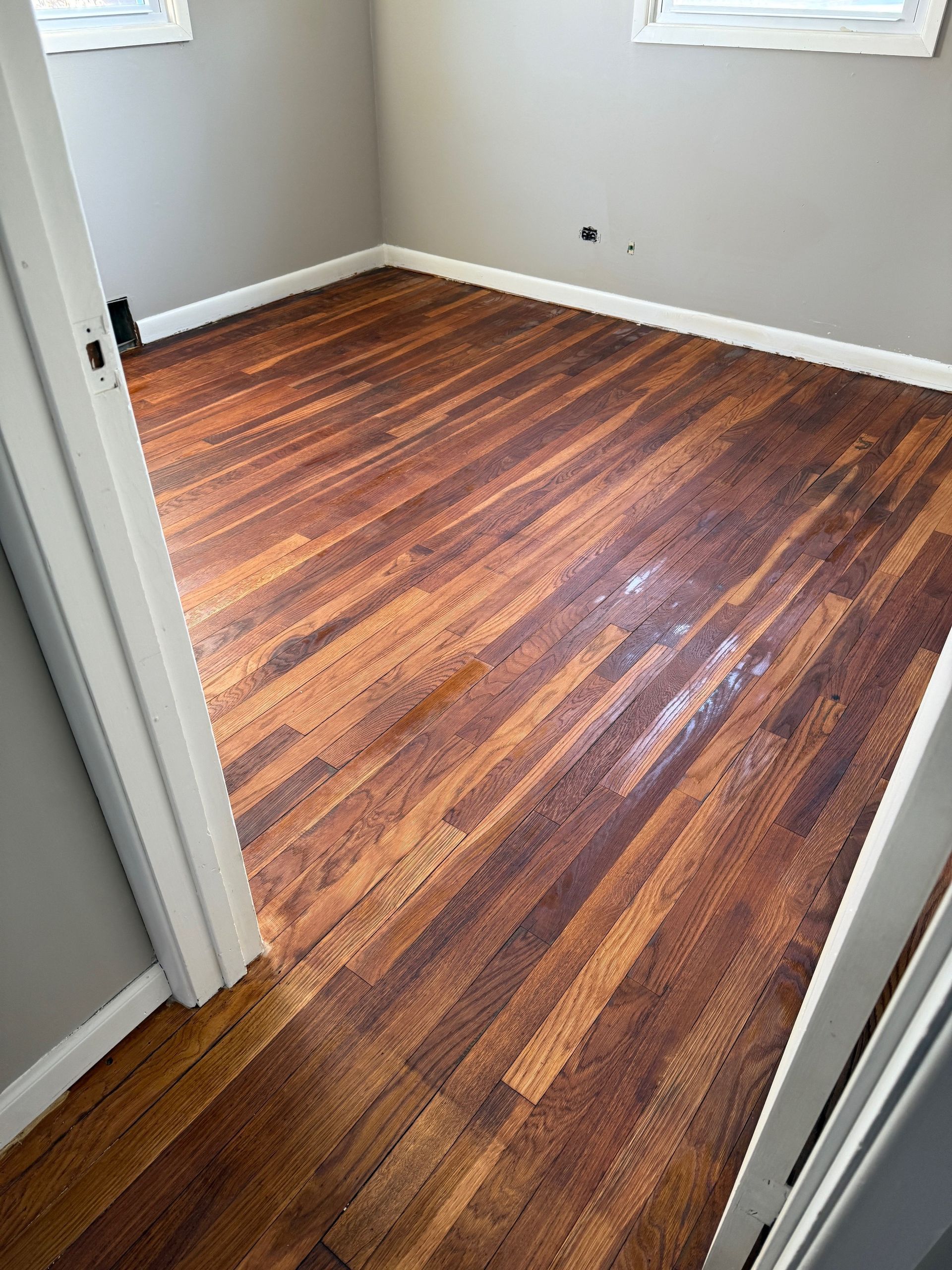 A room with a wooden floor and a door leading into it.