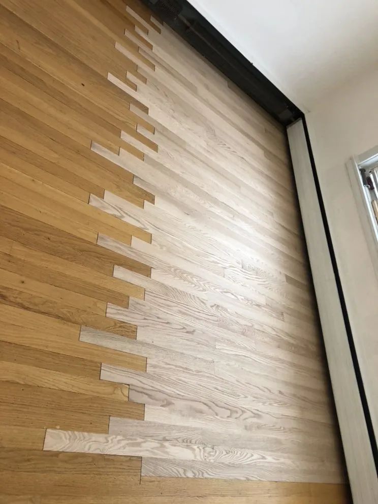 Wooden floor partially sanded, showing a distinct color difference between light and dark wood.