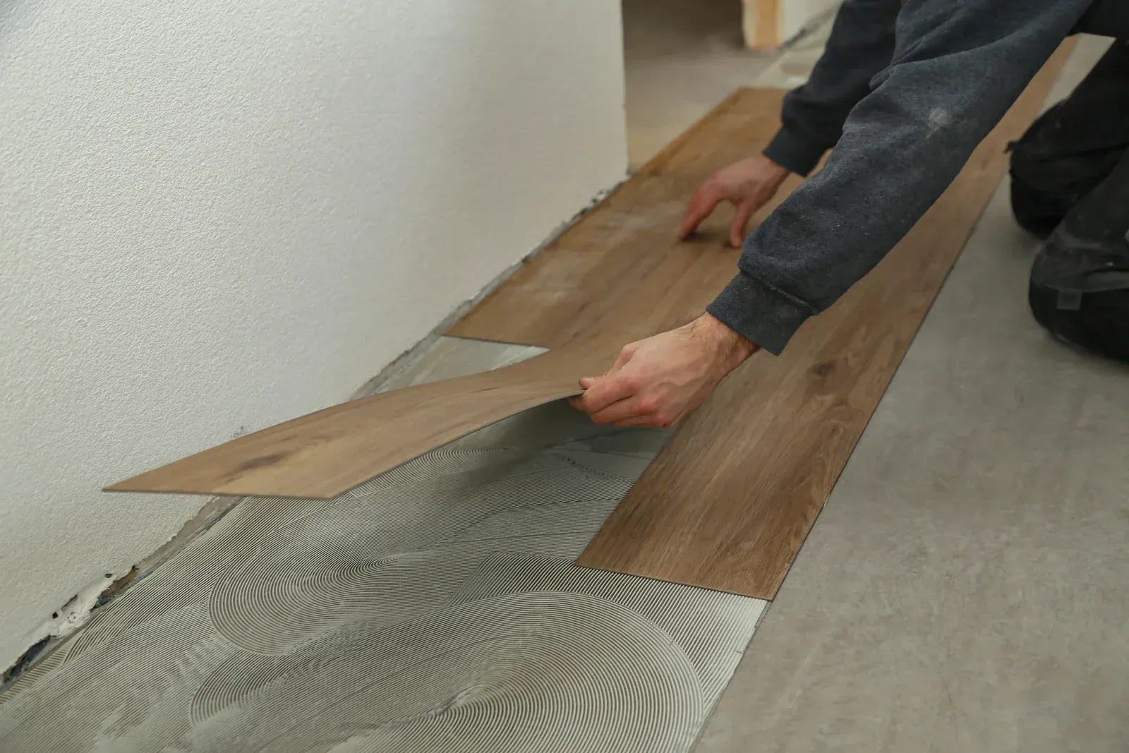 A man is installing a wooden floor in a room.