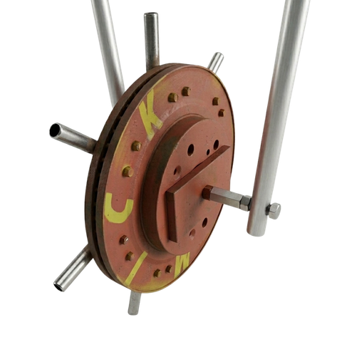 A reddish-brown circular component with metal spokes attached to a frame, marked with yellow letters.
