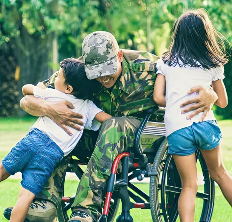 Soldier on a wheelchair hugging two children