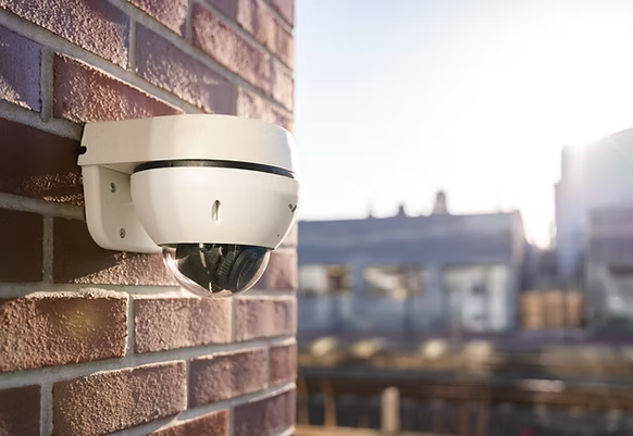 A security camera is mounted on a brick wall.