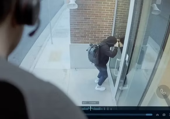 A man is looking at a video of a burglar breaking into a building.
