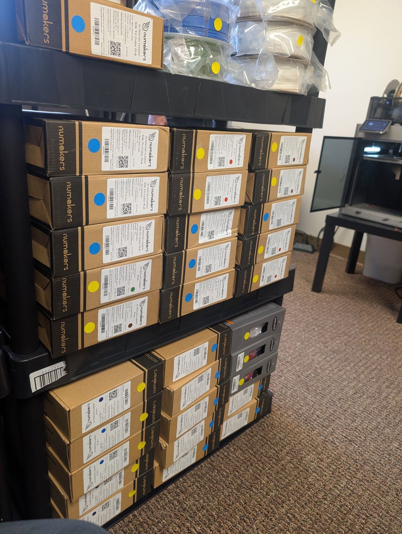 Stacked cardboard boxes of electronics on metal shelves in a storage room.