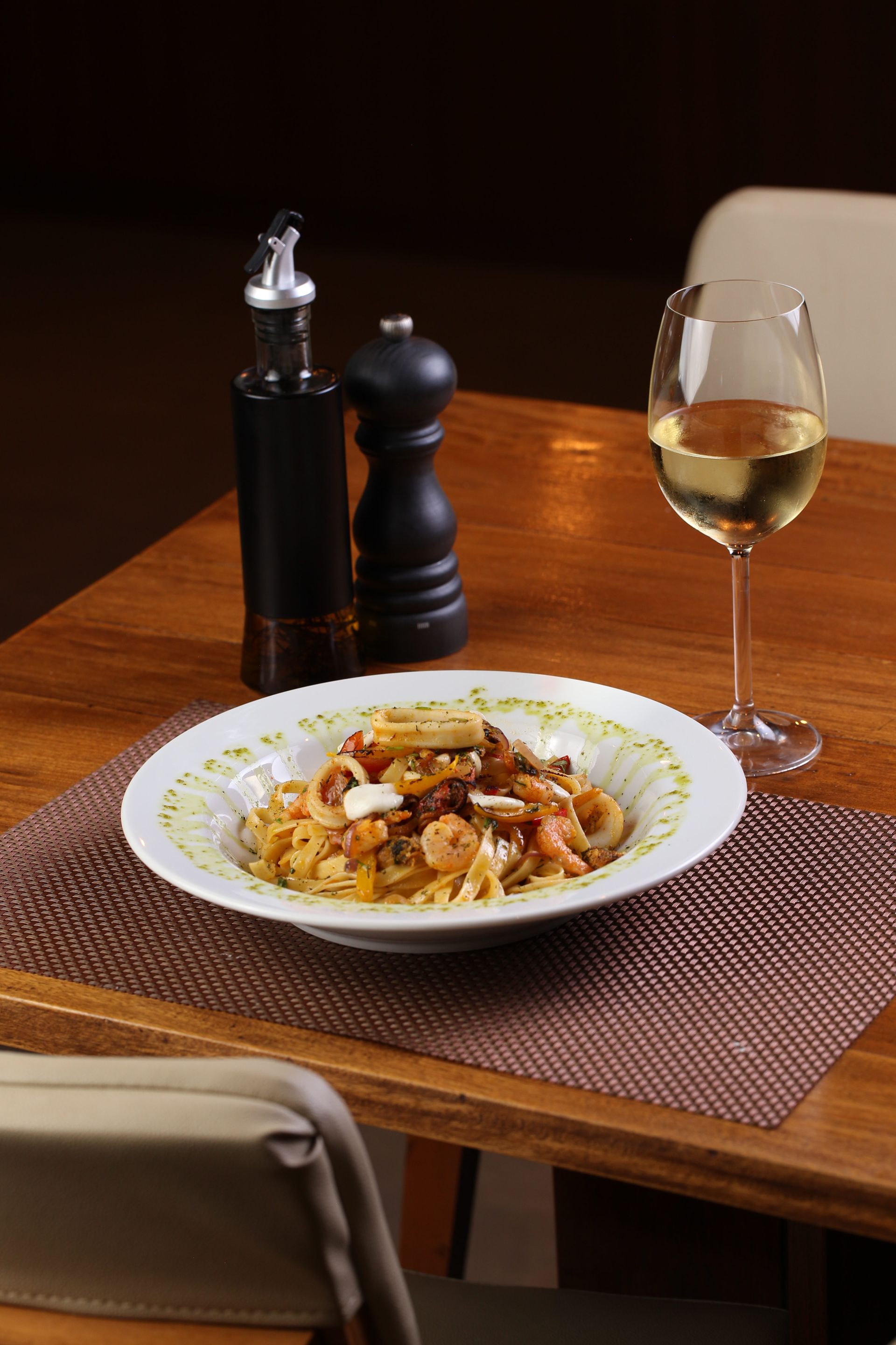 Um prato de macarrão e uma taça de vinho sobre uma mesa.
