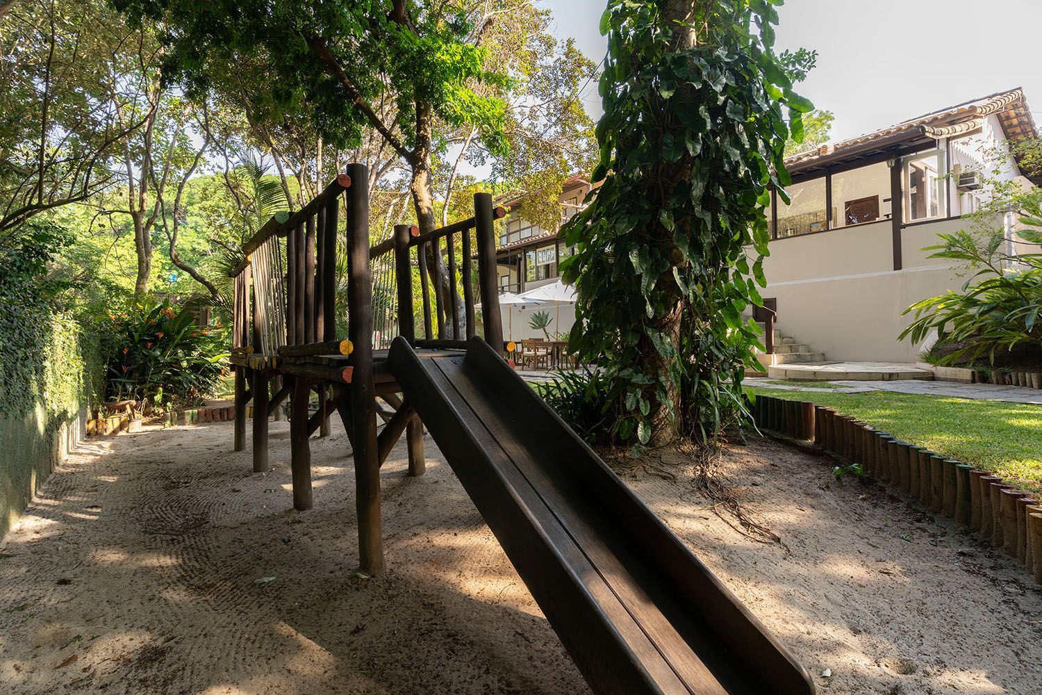 Um escorregador de madeira em um playground com árvores ao fundo.