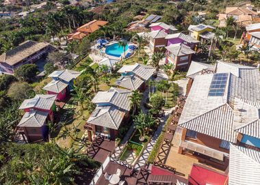 Vista aérea de vilas coloridas com piscina rodeadas por vegetação exuberante.
