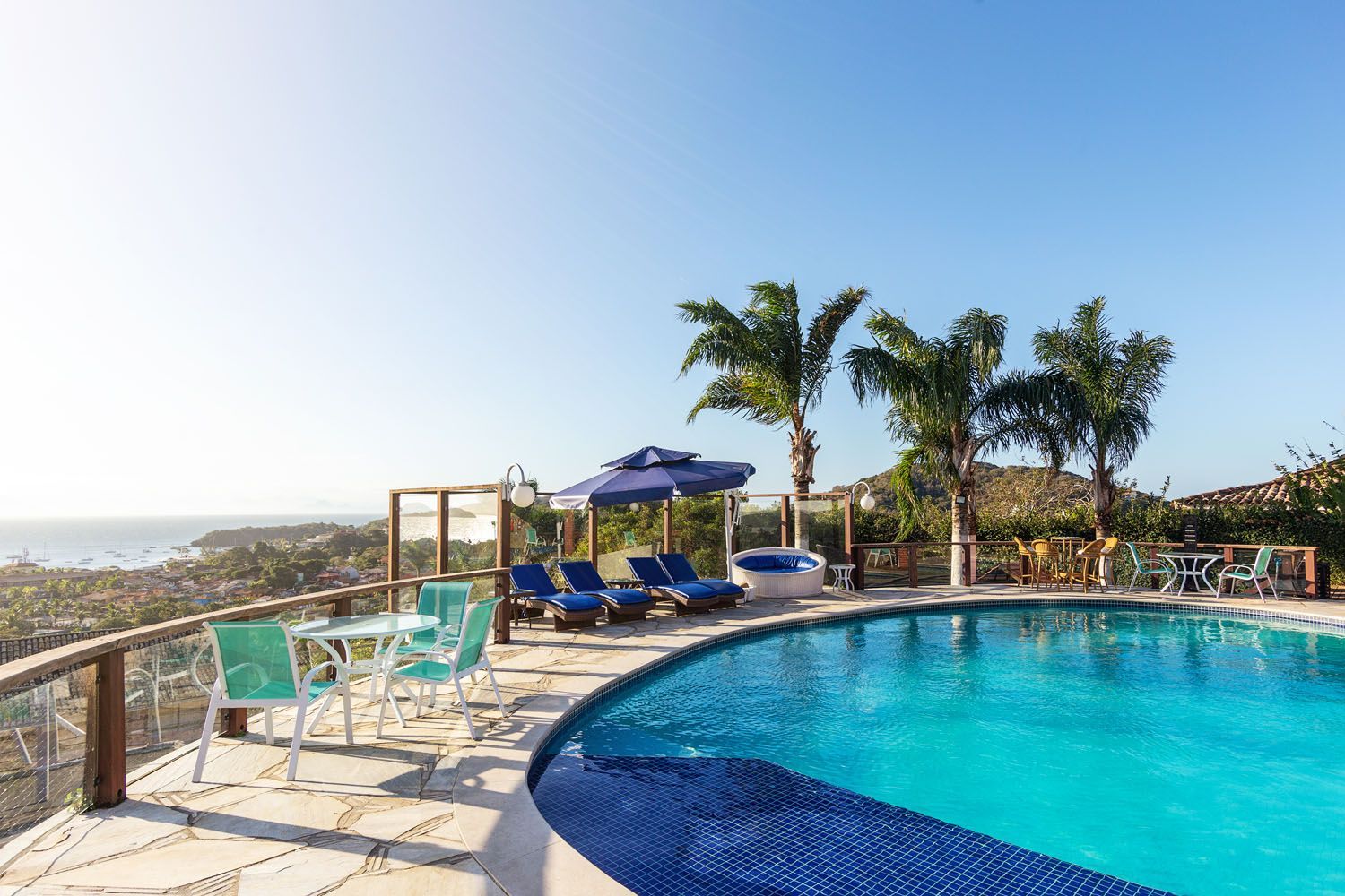 Uma grande piscina cercada por cadeiras e guarda-sóis com vista para o oceano.